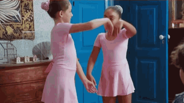 two girls in pink leotards are standing next to each other