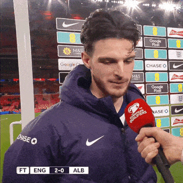 a man wearing a nike jacket is being interviewed
