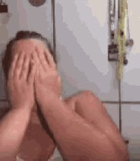 a woman is covering her face with her hands in front of a white wall .