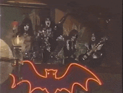 a group of people are playing instruments in front of a neon bat sign .