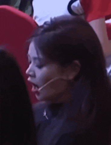 a woman wearing a microphone is sitting in a theatre .