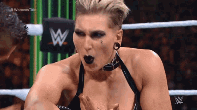 a woman in a wrestling ring with a w logo on the wall