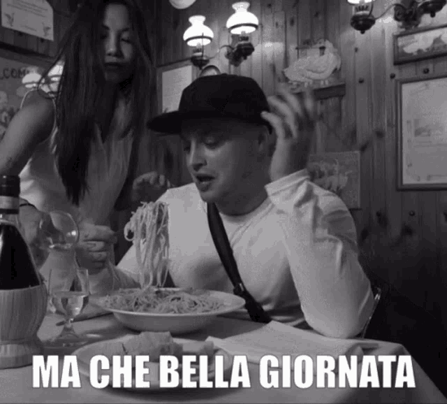 a black and white photo of a man eating spaghetti with the caption ma che bella giornata above him