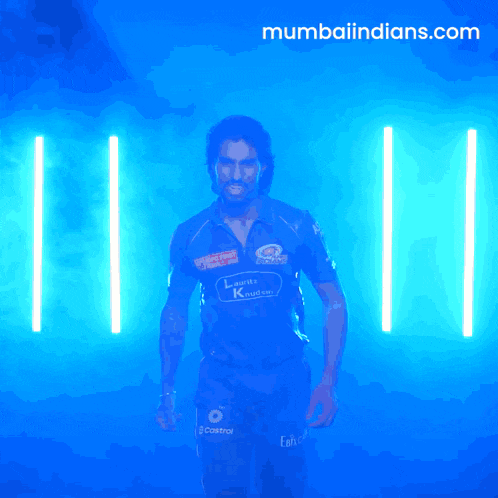 a man in a mumbai indians jersey stands in front of a blue background