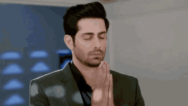a man in a suit is praying with his hands folded in prayer .