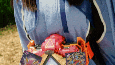 a person in a blue shirt is holding a red object and two cards