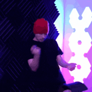 a man wearing a red hat is dancing in front of a wall with a x on it