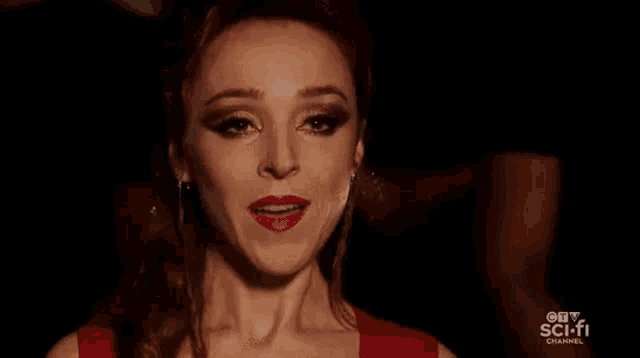 a woman in a red dress is standing in a dark room and saying hello boys .