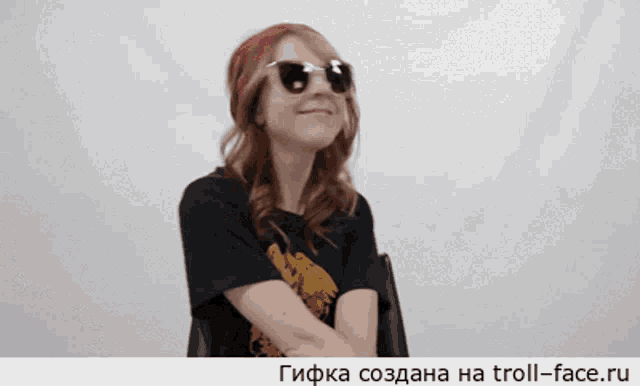 a woman wearing sunglasses and a black t-shirt is smiling
