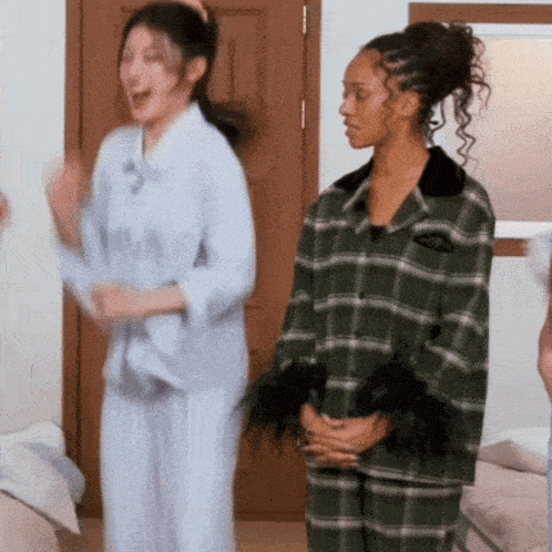 two women in plaid pajamas are dancing in a room