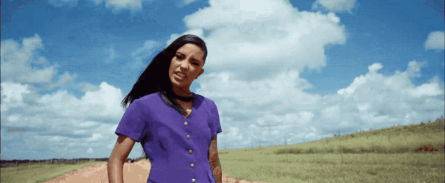 a woman in a purple top is standing in a field