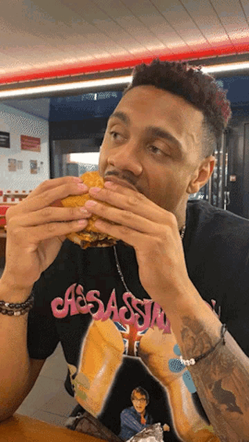 a man eating a hamburger wearing a shirt that says casassian