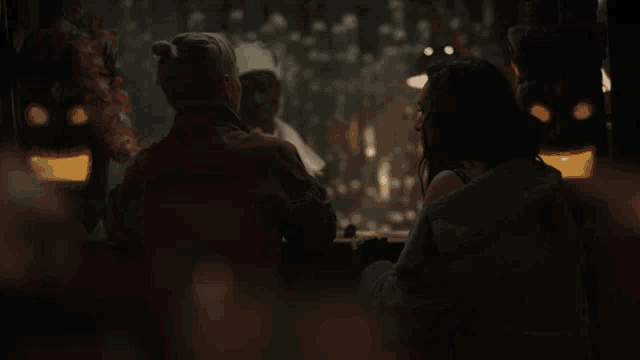 two women are sitting at a table with a man in a chef hat behind them