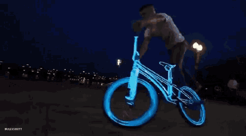 a man is riding a bike that is lit up at night