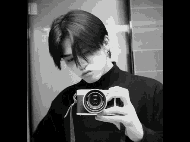 a black and white photo of a man taking a selfie with a camera that says fujinon on it