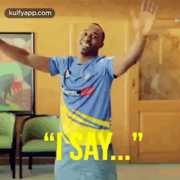 a man in a blue and yellow shirt is standing with his arms outstretched and says i say .