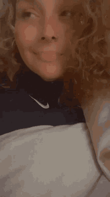a woman with curly hair is wearing a nike sweatshirt