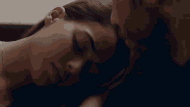 a close up of a woman 's face with a man 's face in the background