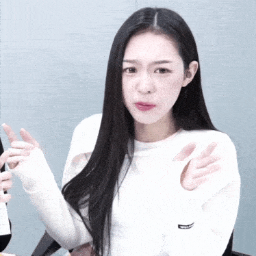 a woman with long black hair is wearing a white sweater that says wolf on it