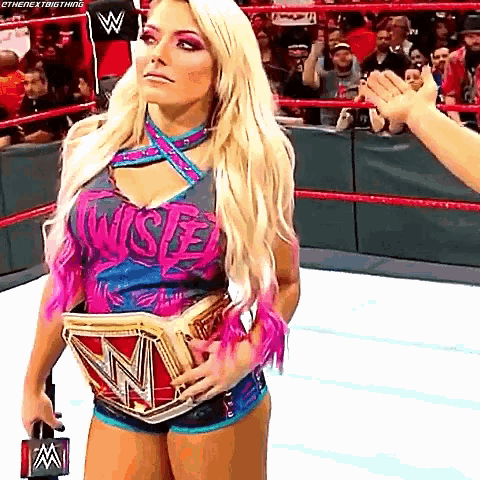 a woman in a wrestling ring is holding a championship belt .