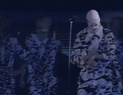 a man wearing a white mask is standing in front of a microphone