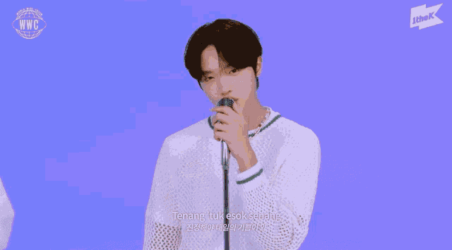 a young man singing into a microphone with jtbk written on the bottom