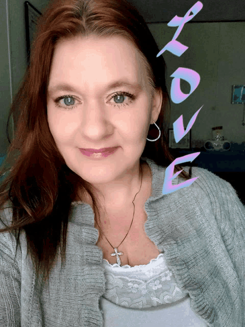 a woman wearing a gray cardigan and a white tank top with the word love behind her