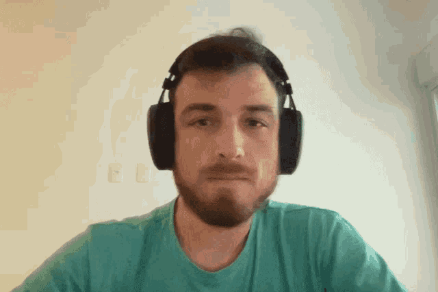 a man with a beard wearing headphones looks at the camera