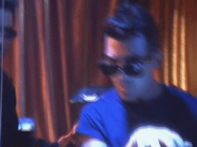 a man wearing sunglasses is sitting in front of a keyboard .