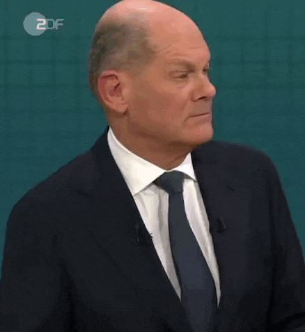 a bald man in a suit and tie is talking on a tv show .
