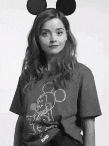 a black and white photo of a woman wearing mickey mouse ears and a mickey mouse t-shirt