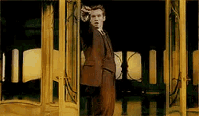 a man in a suit is standing in front of a glass door .