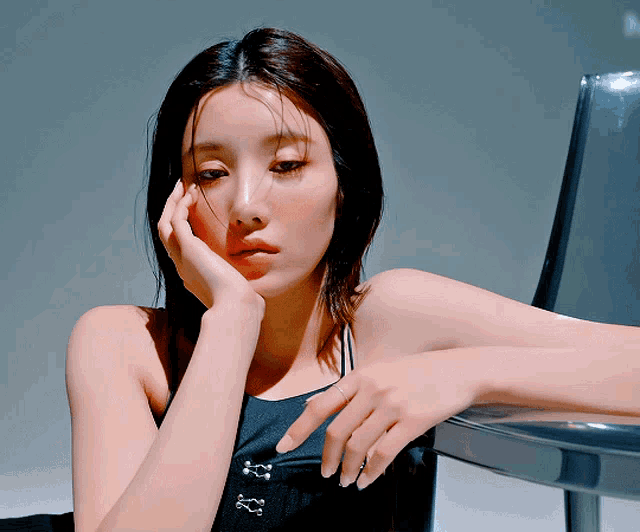 a woman leaning on a chair with her hand on her chin