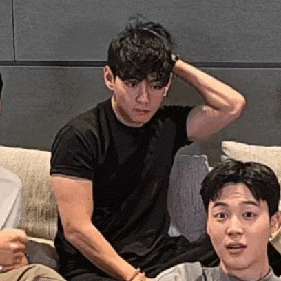 a group of young men are sitting on a couch and one of them is holding his hand to his head .