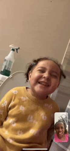a little girl in a yellow sweater is sitting on a toilet