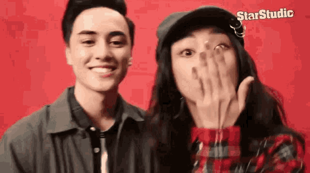 a man and a woman are posing for a picture and the woman is covering her face .