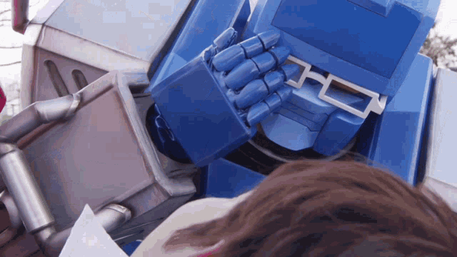 a close up of a blue robot 's arm with the letter o on the bottom