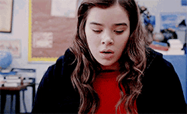 a girl in a red sweater and black jacket is making a funny face