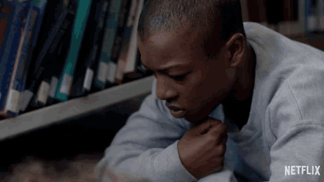a man laying on the floor in front of a bookshelf with netflix written on the bottom right