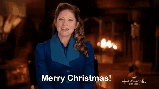 a woman sitting in front of a fireplace with the words merry christmas on the bottom