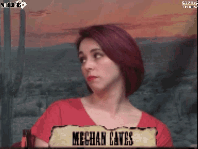 a woman with red hair is sitting in front of a sign that says meghan caves