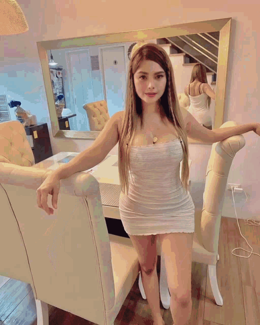 a woman in a pink top and shorts is taking a selfie in front of a wall with a clock on it