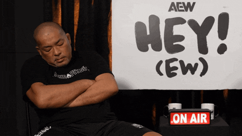 a man sitting in front of a sign that says hey