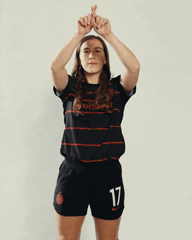 a woman with the number 17 on her shorts is raising her arms in the air