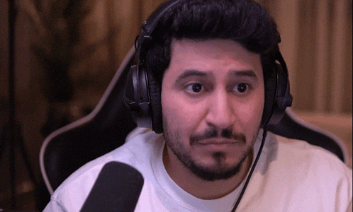 a man with a beard wearing headphones is sitting in front of a microphone .
