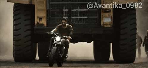 a man is riding a motorcycle in front of a large truck with the hashtag avantika_0902