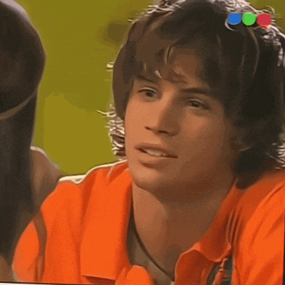 a young man wearing an orange shirt is looking at a woman