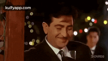 a man in a suit and tie is drinking from a glass of wine .