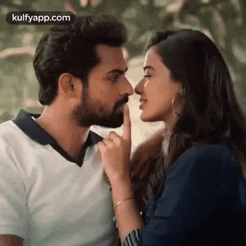 a man and a woman are kissing and the woman is putting her finger to the man 's nose .