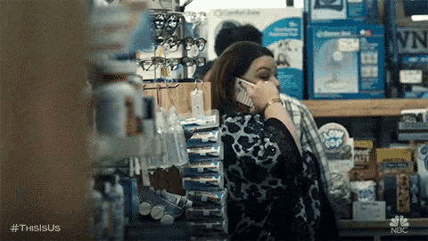a woman is standing in a store talking on a cell phone .